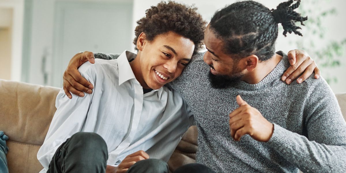 Dad and male teen hugging