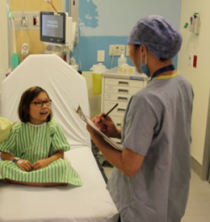 Child in hospital bed talking to medical staff