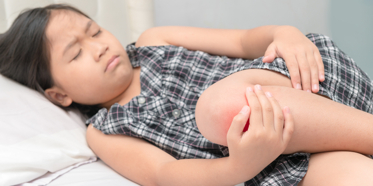 Child with joint pain holding knee